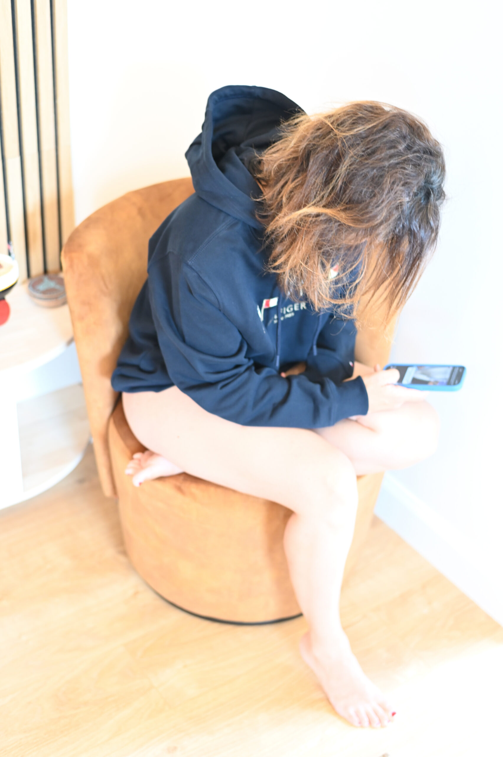 Klara-i-Tommy-Hilfiger-hoodie-på-vit-fåtölj